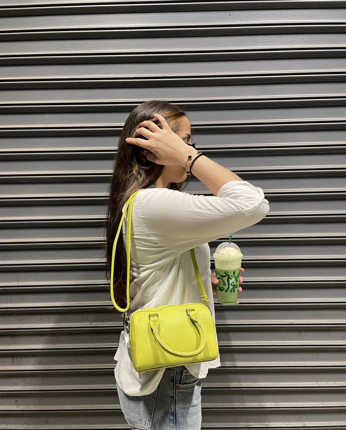 Susana con bolso lima frente a una persiana metálica