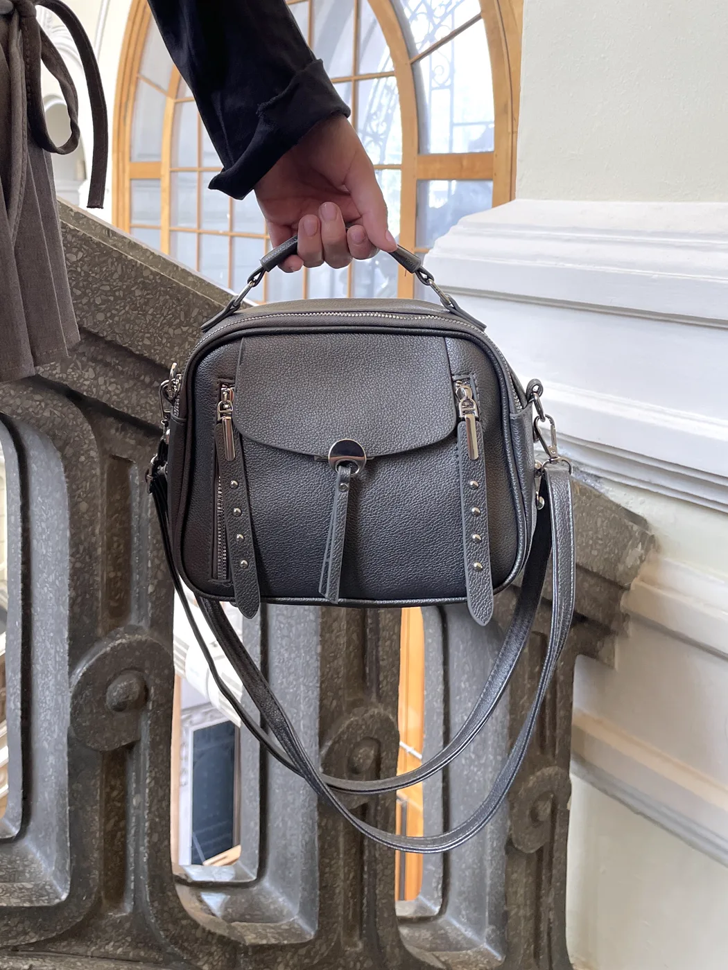 Bolso gris de piel sostenido en alto