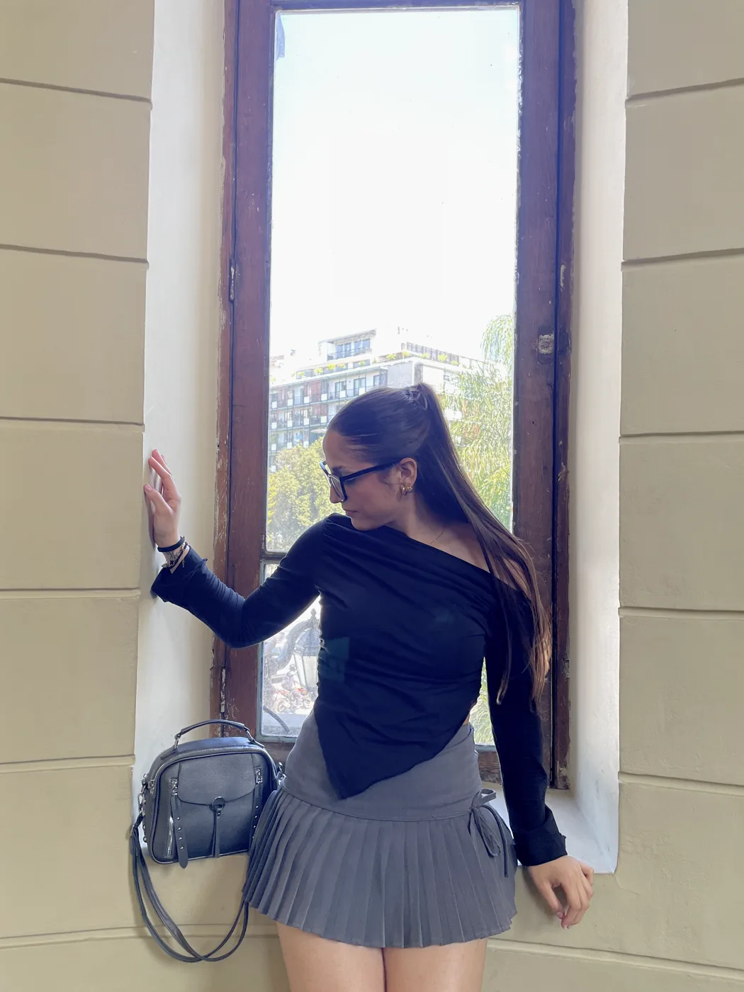 Susana junto a una ventana con bolso gris
